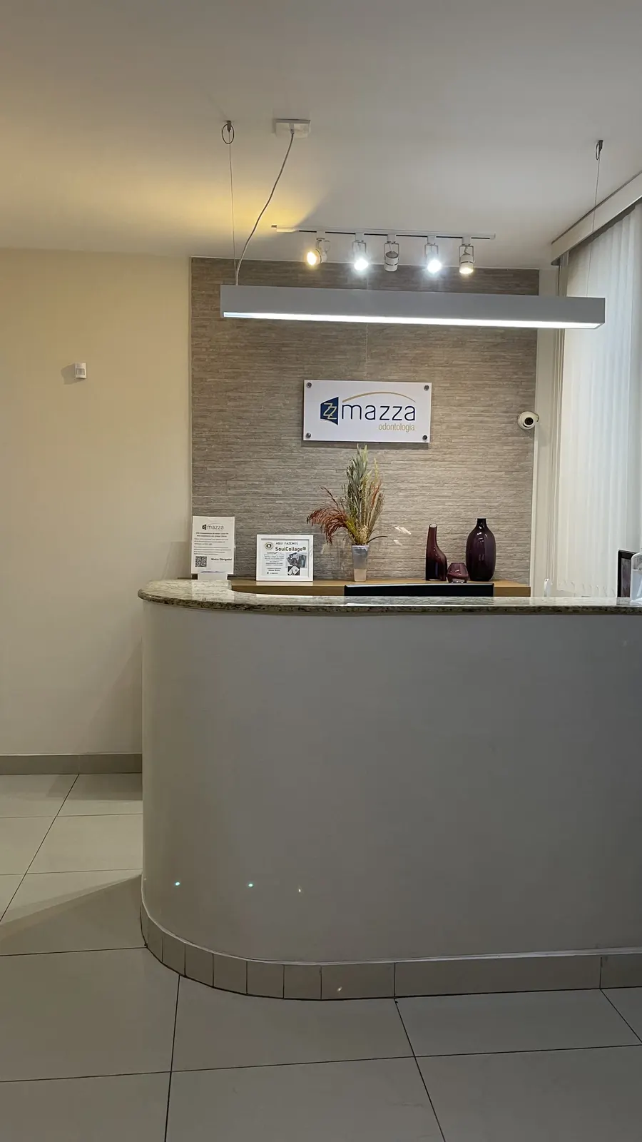 Recepção da Clínica Mazza com balcão curvo e iluminação dedicada