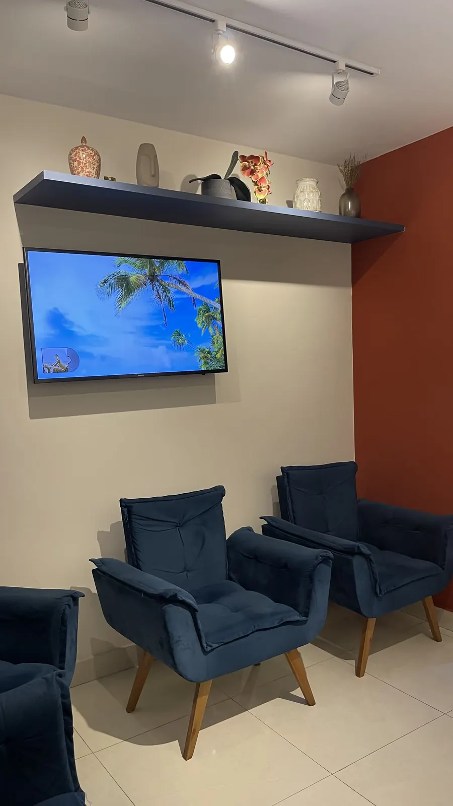 Sala de espera aconchegante com poltronas azuis e TV