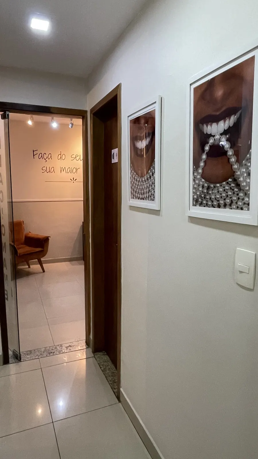 Corredor interno com quadros decorativos e frase inspiradora ao fundo