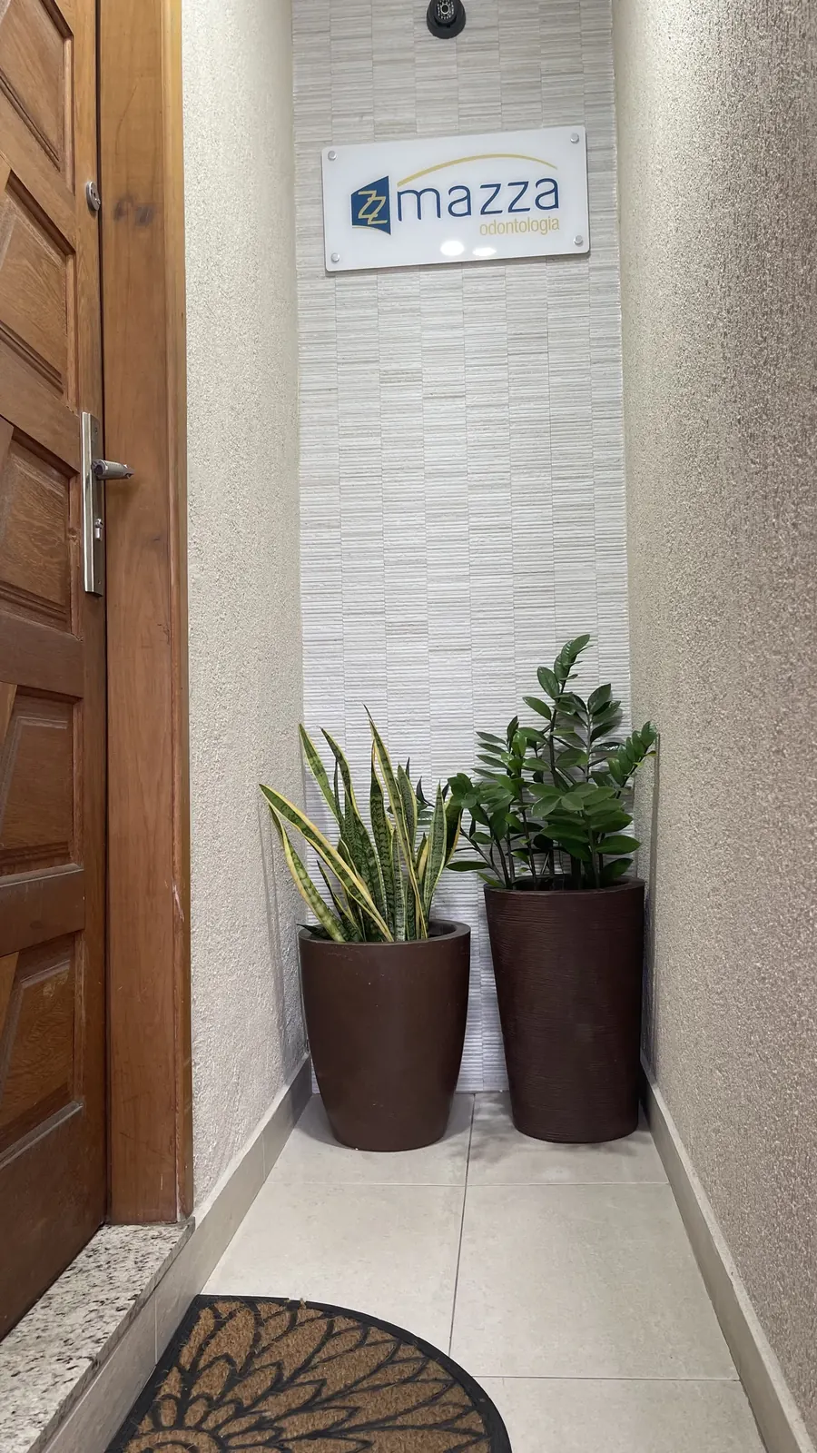 Entrada da Clínica Mazza Odontologia com placa e plantas ornamentais