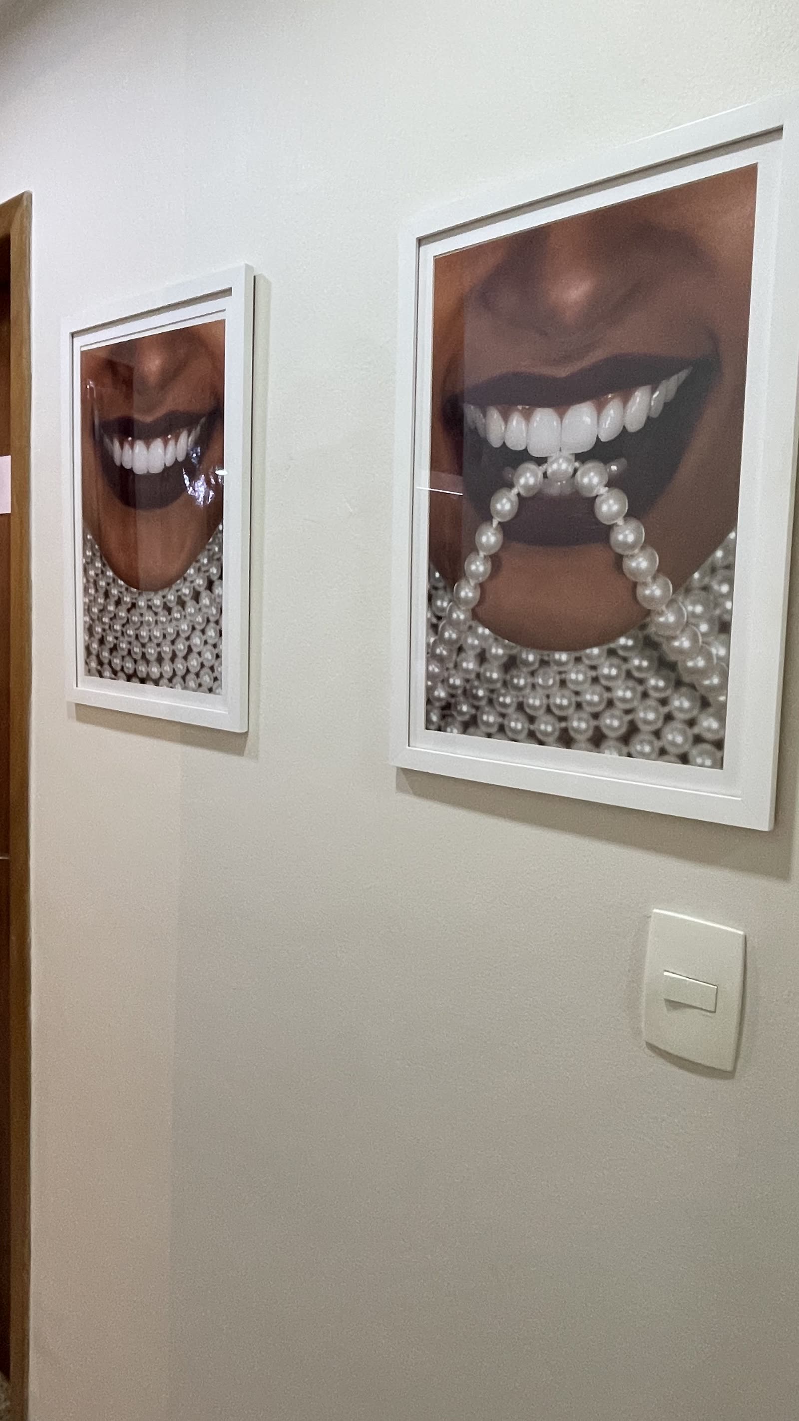 Quadros decorativos de sorrisos harmônicos no corredor da clínica